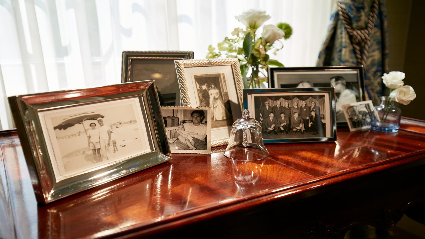 Old images framed and sitting on top of a table near a window inside a funeral home. 