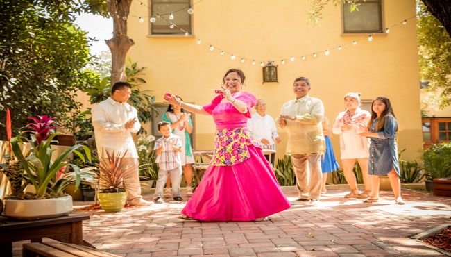 A woman in a fuschia dress performs a dance at an outdoor reception.