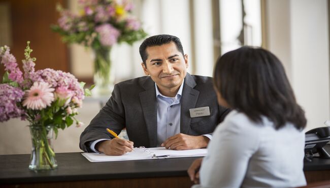 A Dignity Memorial associate speaking with a client while sitting at a desk. 