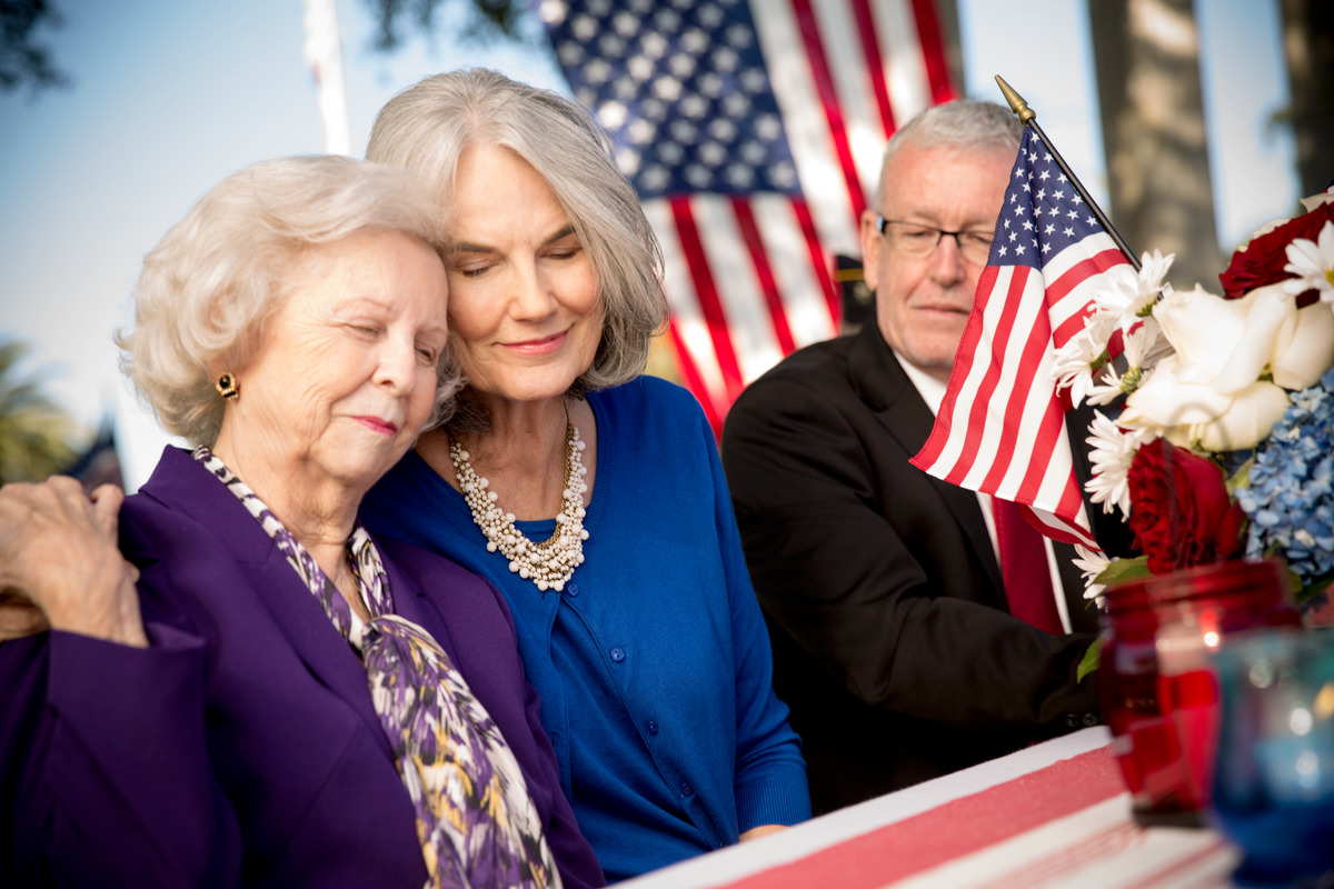 A mother and daughter comfort one another during a ceremony for a veteran.