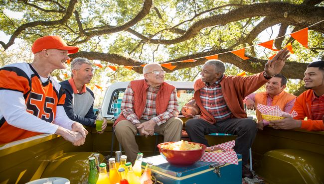  A group of men sitting in the back of a pick-up truck share stories.