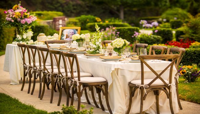 Beautiful outdoor table setting with an urn, portrait and flowers.