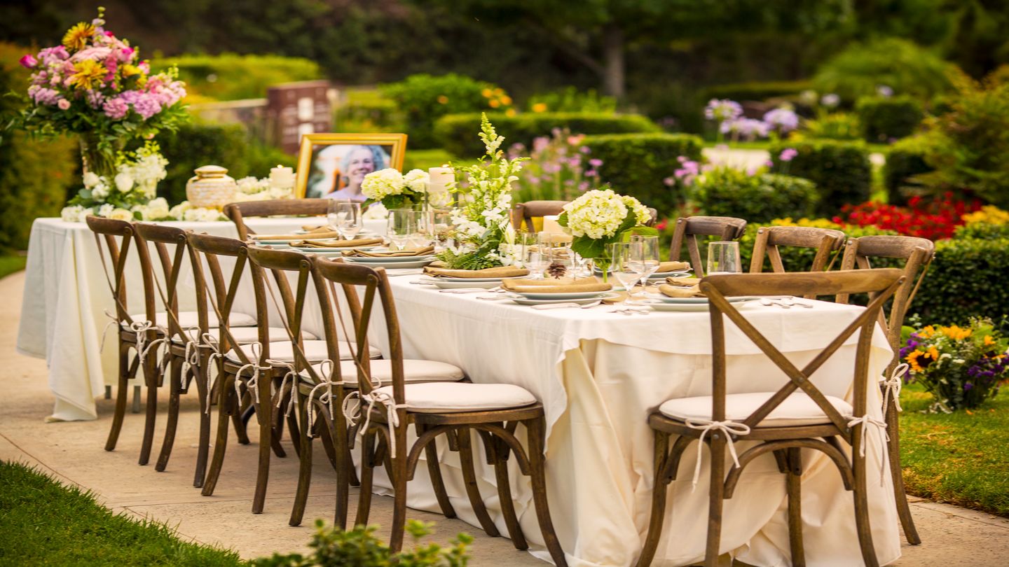 Beautiful outdoor table setting with an urn, portrait and flowers.