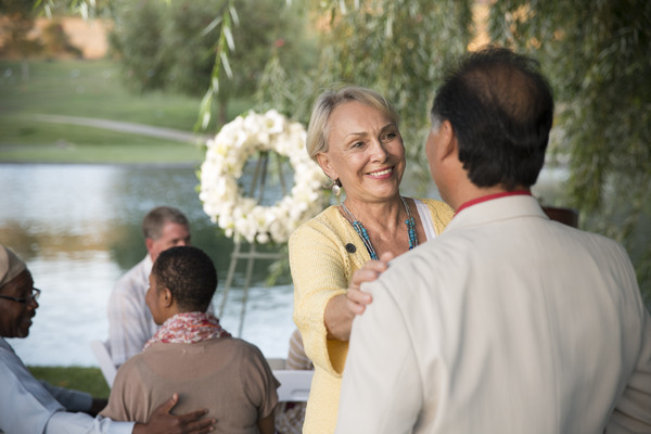 A woman talking to a man with her hand on his shoulder while standing outdoor at service.