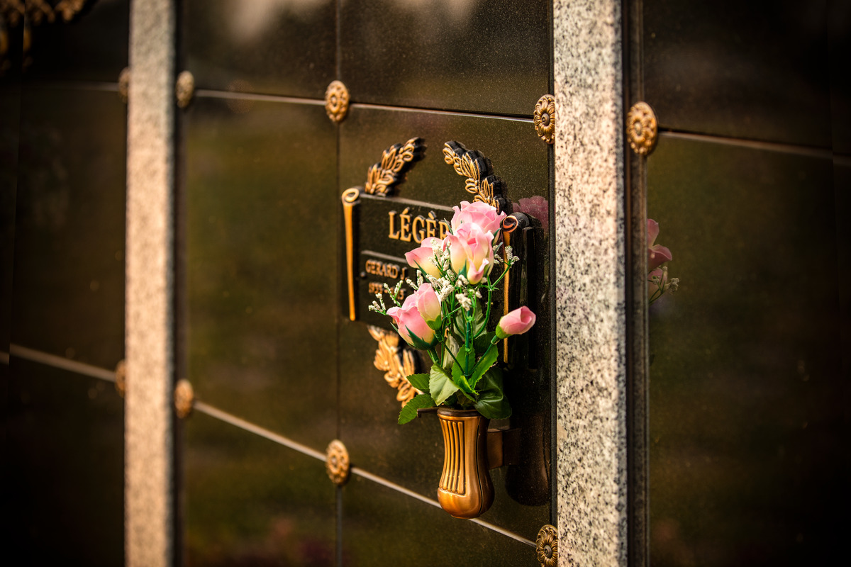Granite-front cremation niche with bronze plaque and vase.