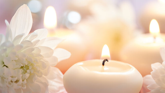 A serene setting of white candles and flowers evokes peace and tranquility. 
