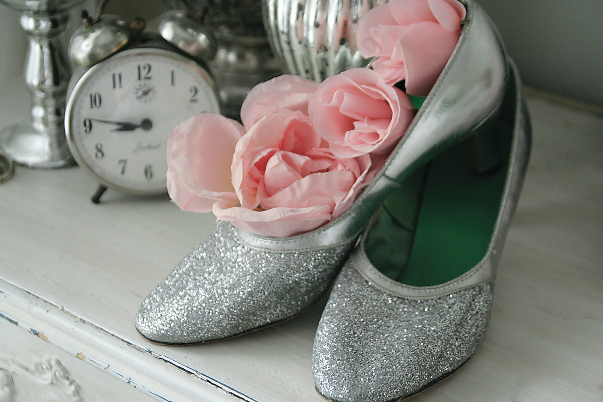 Silver glitter flats with pink flowers in them sitting on a dresser next to an alarm clock