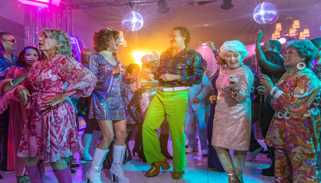 A group of people dancing at a disco-themed memorial