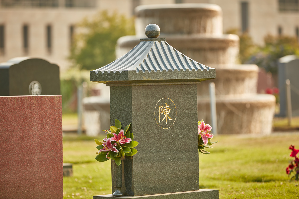 An upright memorial with Asian symbol and fountain in the background at Ocean View Funeral Home and Burial Park