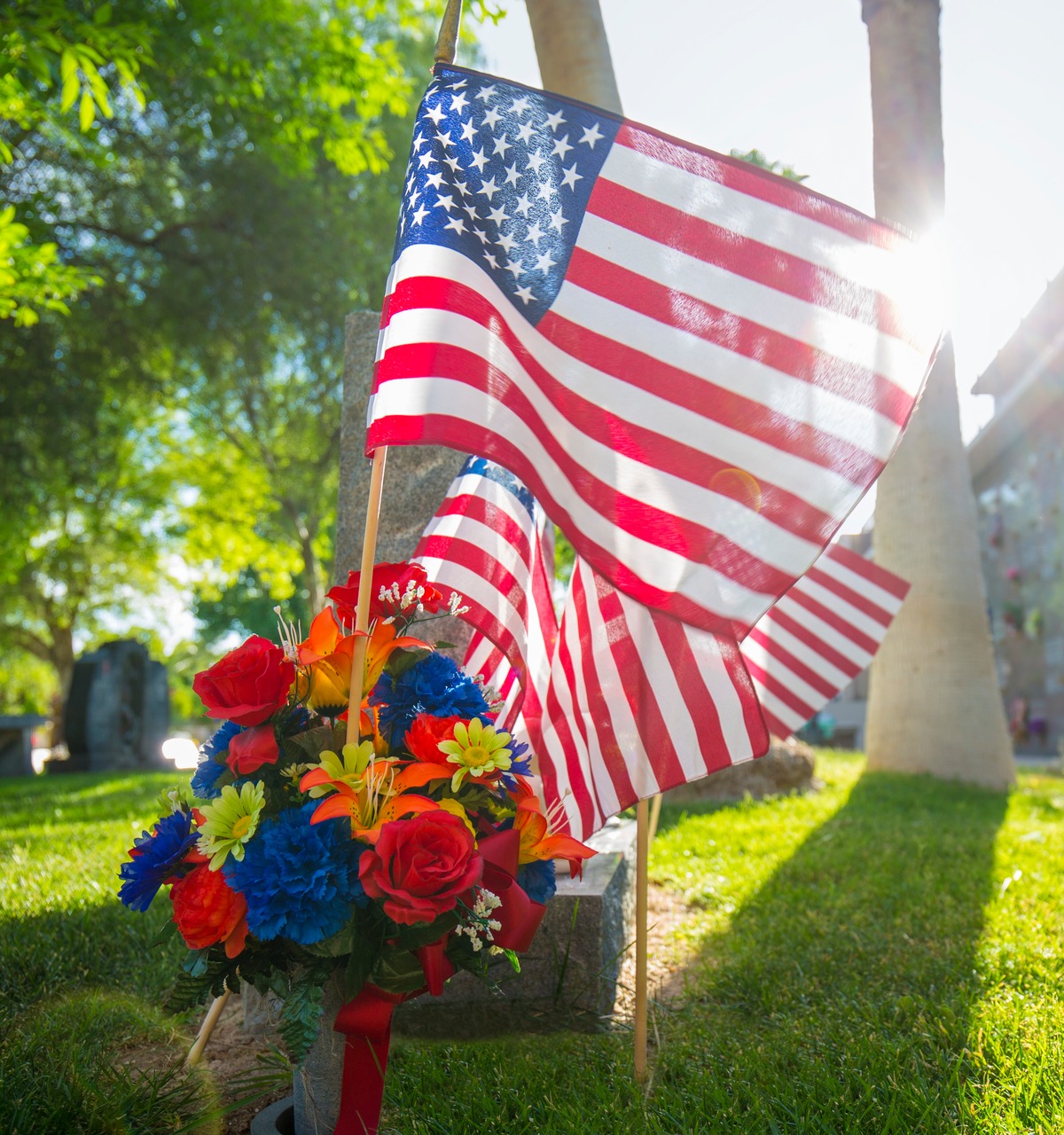 Close-up of American flags and flowers on marker in cemetery outside at Palm.
