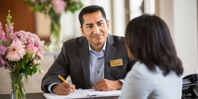 A Dignity Memorial associate speaking with a client while sitting at a desk. 
