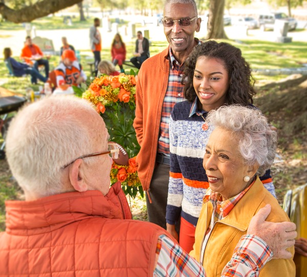 Two men and two ladies talking at a tailgate celebration.