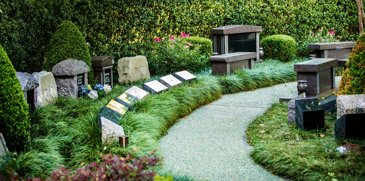 Pathway through a cremation garden in a cemetery with niches, boulders and benches. 