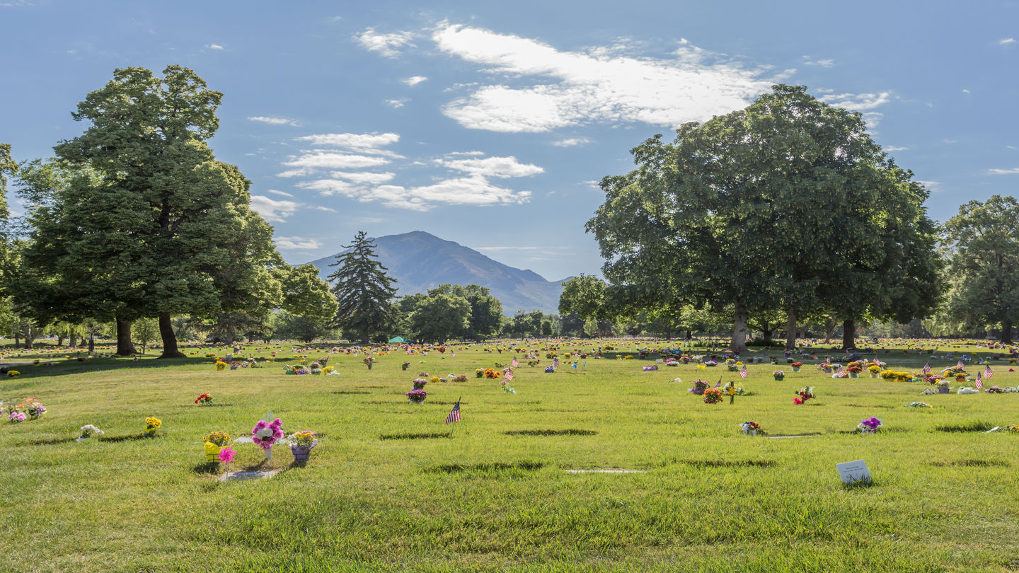 Cemetery grounds with flat markers and a view of the mountains at Wasatch Lawn Memorial Park.