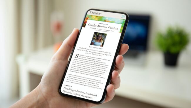 Someone holding a mobile phone looking at an obituary