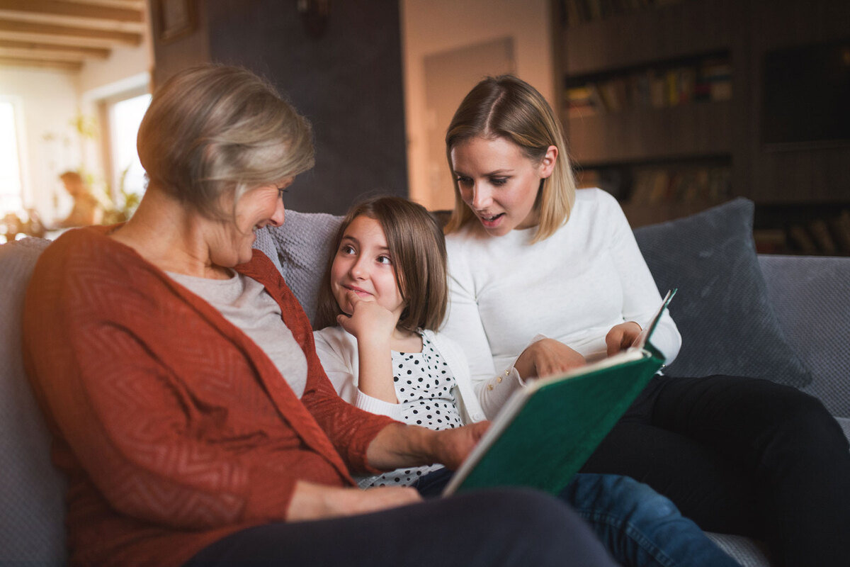 Grandmother, mother, and daughter looking at a photo album together