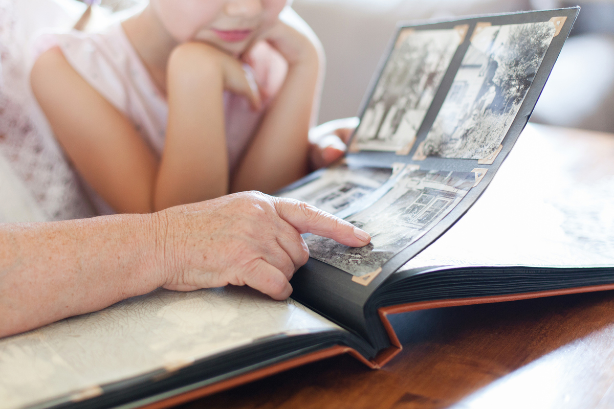 Grandmother and granddaughter looking at old photo album at home