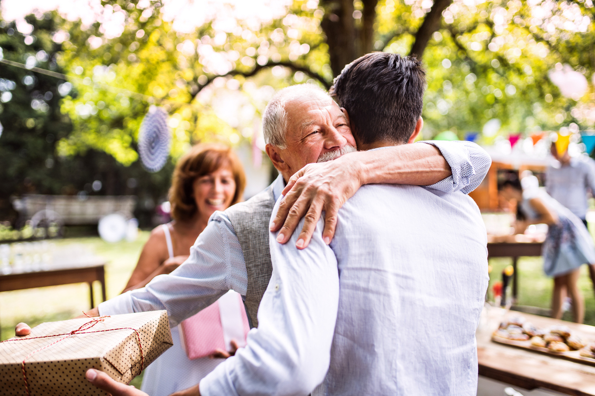 man hugging adult son at outdoor party