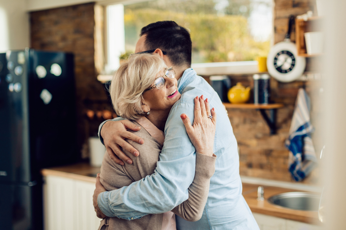 mother and adult son hugging in kitchen