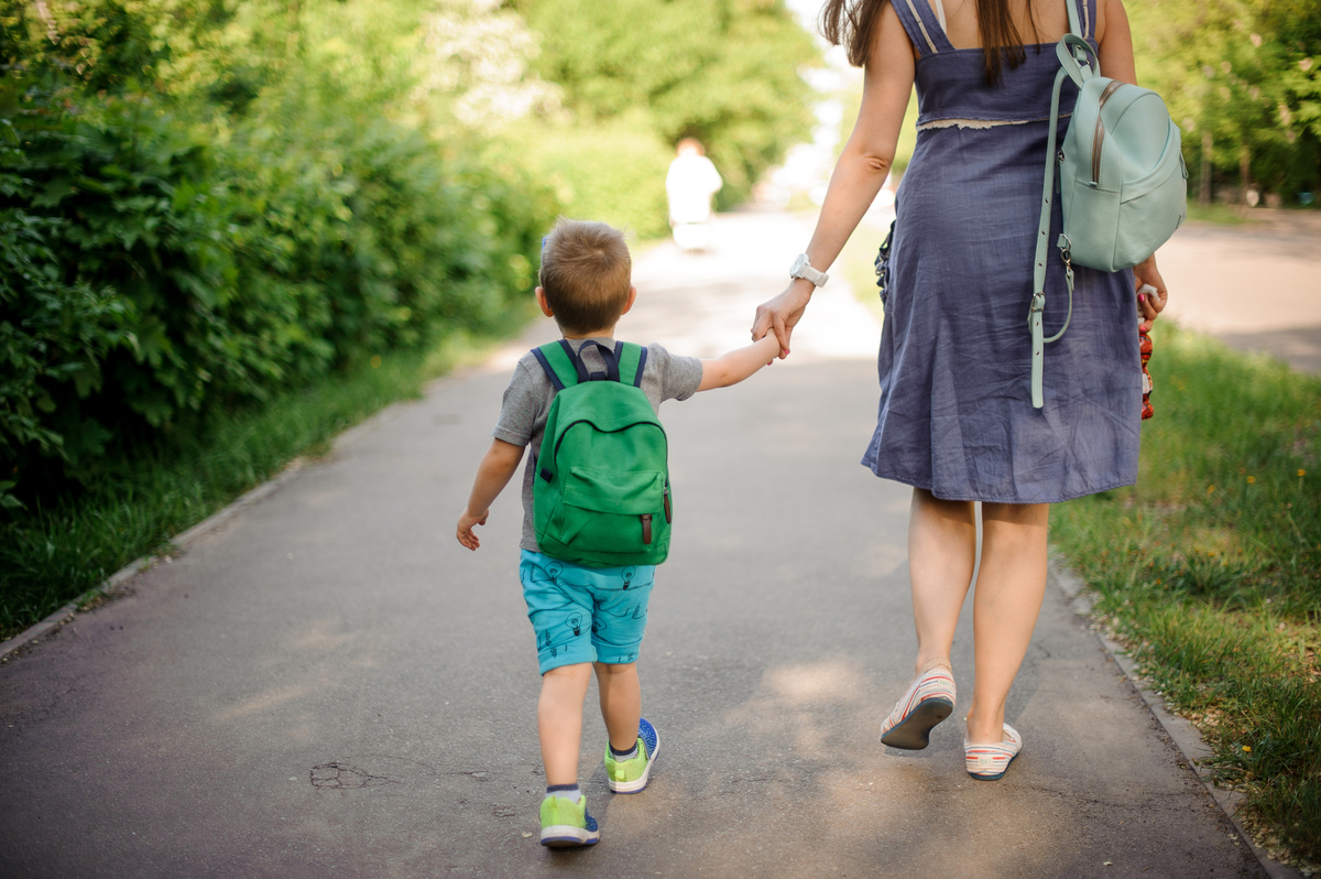 boy holding hands with his mother on a walk
