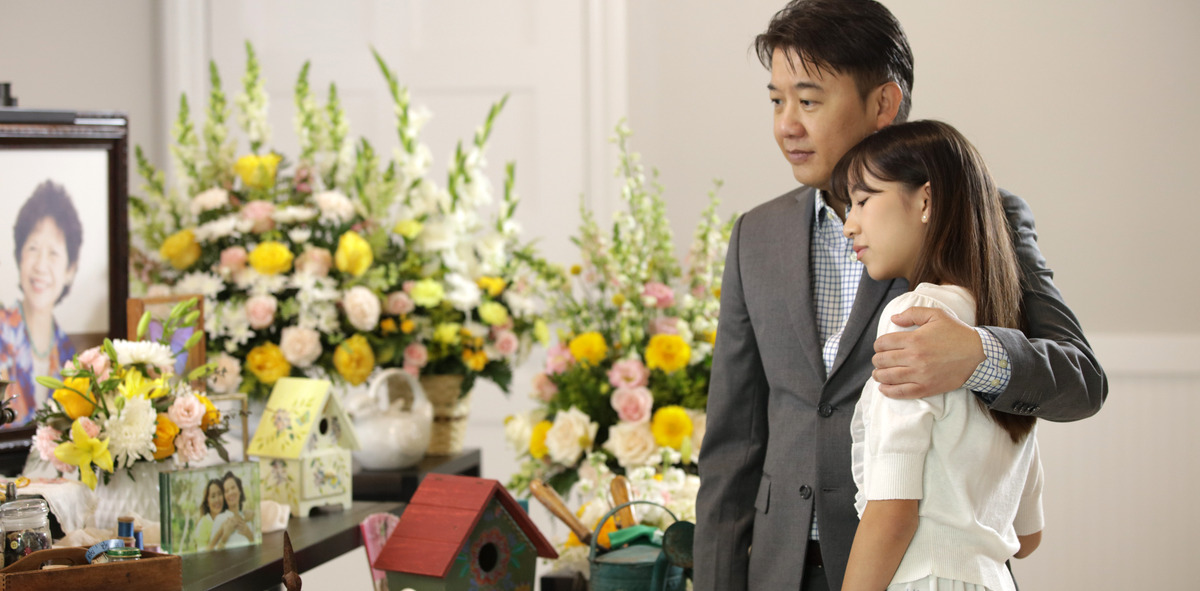 A father puts his arm around his daughter as they admire a Memory Table at a celebration of life.