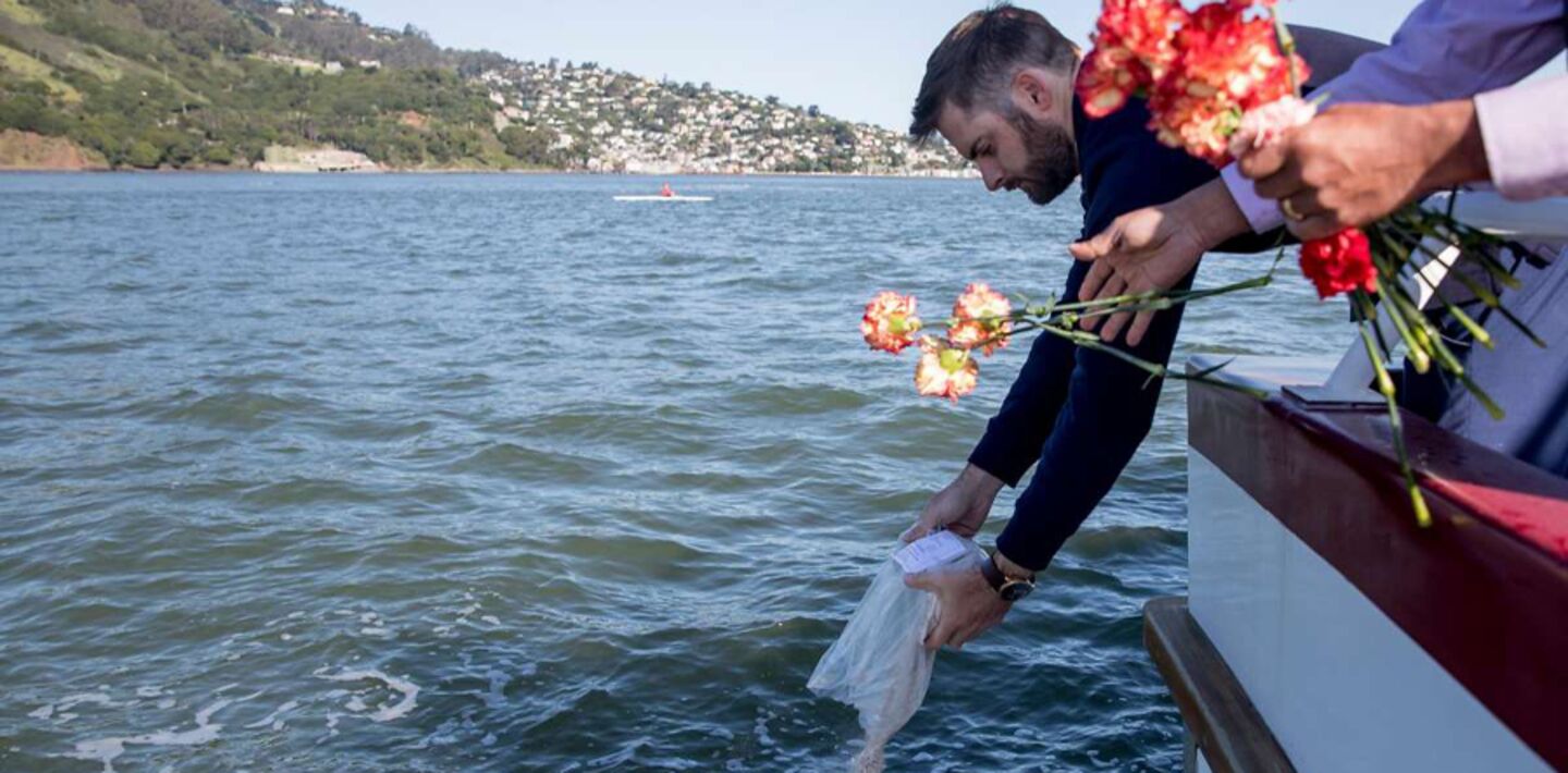 Man scattering ashes into sea from side of boat
